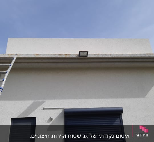 סולם מתכת ליד קיר עם חלון ותריס סגור